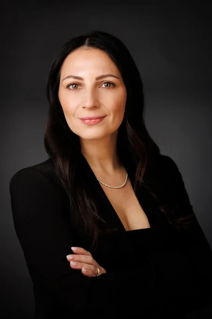 Smiling woman in professional attire, dark background.