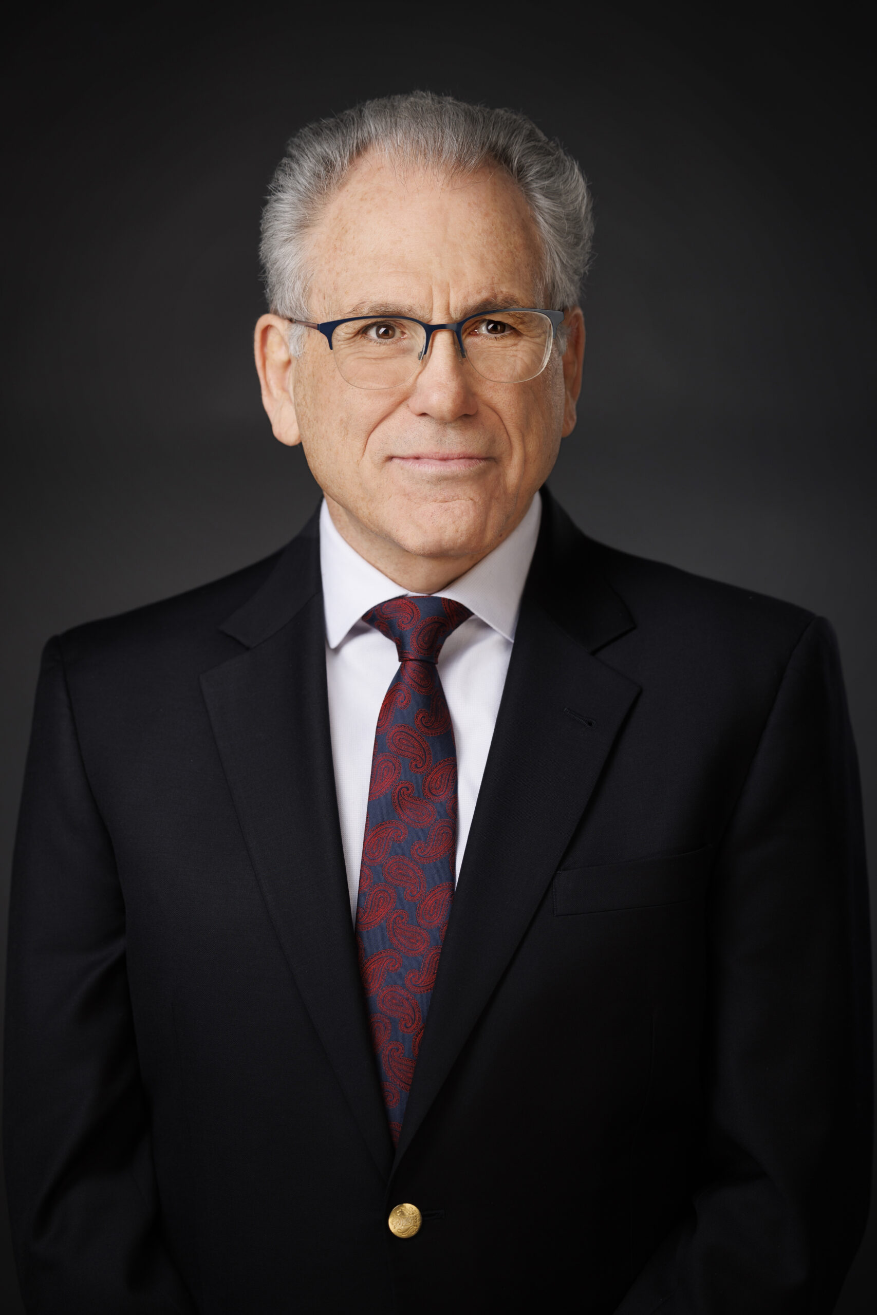 Professional portrait of an older man in a suit and tie.